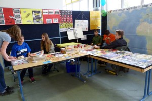 Schüler präsentieren an Tischen verschiedene Materialien und Projekte.