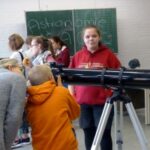 Schülerinnen und Schüler stehen bei einem Astronomie-Workshop um ein Teleskop.