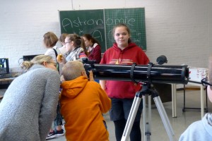 Schülerinnen und Schüler stehen bei einem Astronomie-Workshop um ein Teleskop.