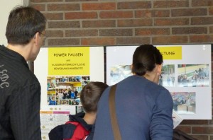 Besucher betrachten Informationen an Plakatwänden in einer Schule.