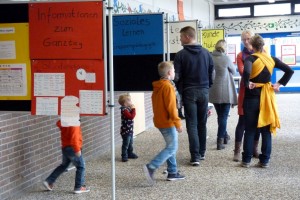 Besucher in einer Schule betrachten Informationsstände in einem Flur.