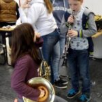 Vier Kinder in einem Raum, zwei spielen Musikinstrumente, andere stehen daneben.