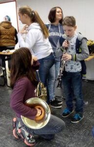 Vier Kinder in einem Raum, zwei spielen Musikinstrumente, andere stehen daneben.