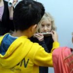 Kinder halten Instrumente und interagieren miteinander.