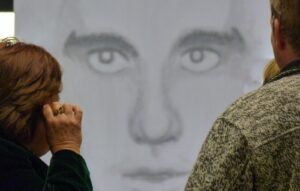 Blick auf ein zeichnerisches Porträt, das von zwei Personen betrachtet wird.