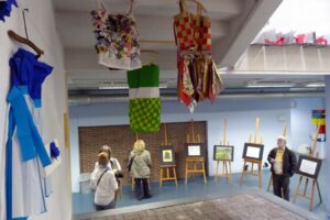 Kunstwerke und Kleidungsstücke hängen in einem Ausstellungsraum aus.
