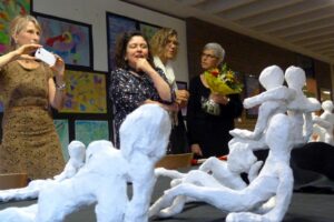 Kunstwerke aus Ton und Teilnehmer bei einer Ausstellung in einem Schulgebäude.