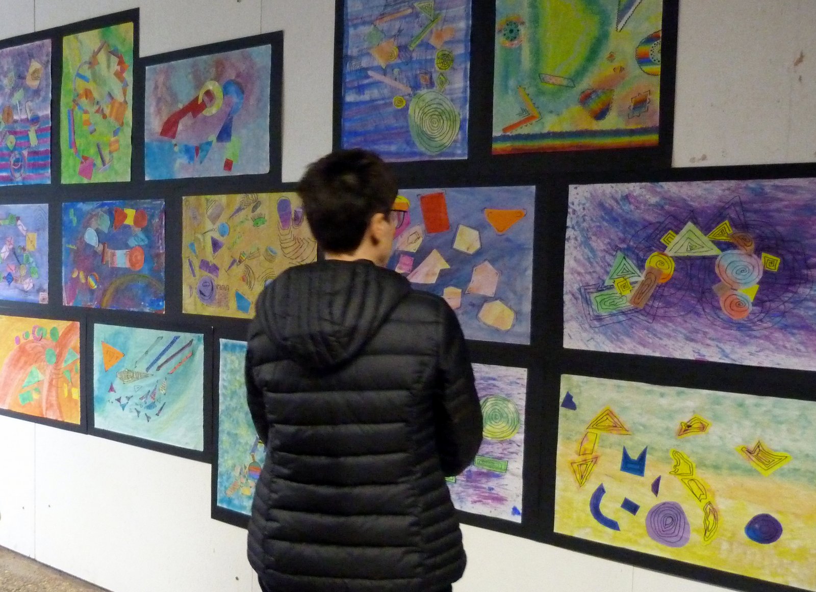 Besucher betrachtet eine Ausstellung mit bunten Zeichnungen an der Wand.