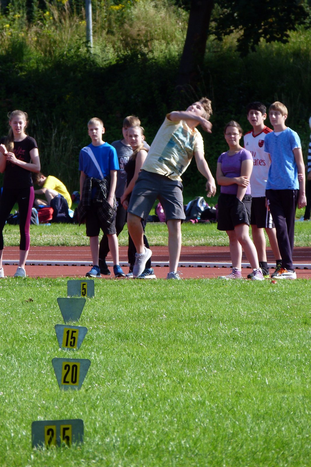 Schüler werfen im Sport Wettkampf; 5, 15, 20 und 25 Meter Markierungen sichtbar.