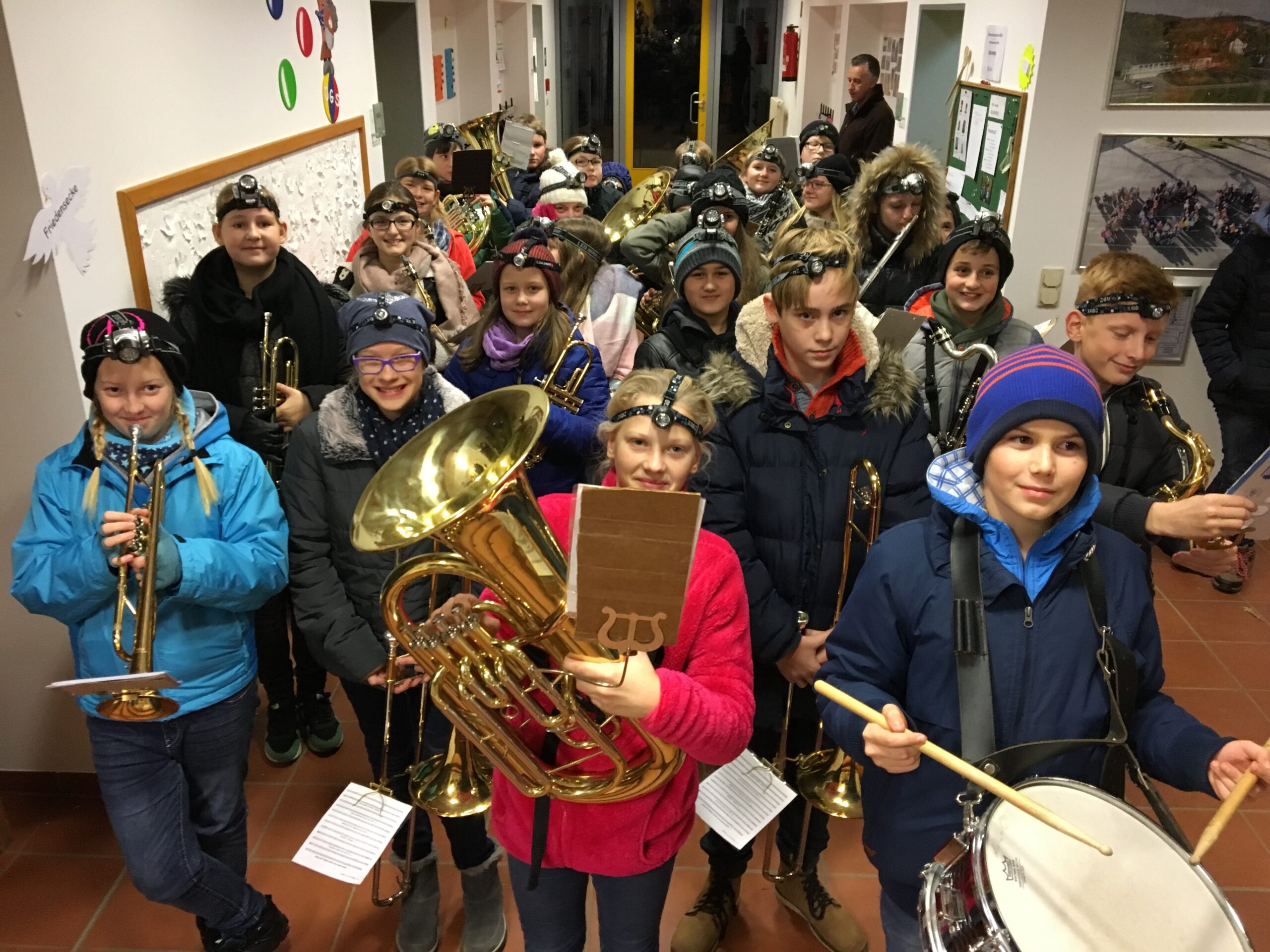 Schüler in Musikgruppen mit Instrumenten in einem Flur.