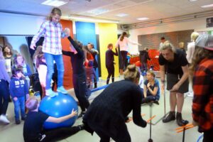 Gruppenevent in einer Turnhalle mit Kindern und Jugendlichen, die verschiedene Aktivitäten durchführen.