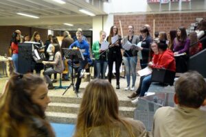 Schülerinnen und Schüler führen einen musikalischen Auftritt in der Aula auf.