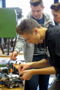 Schüler arbeiten an einem technischen Projekt am Tisch.