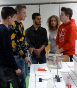 Fünf Schüler diskutieren in einem Klassenraum über ein Experiment.
