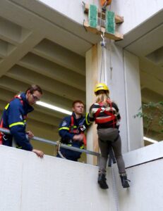 Bergungsübung: Person in Sicherheitsausrüstung wird abgeseilt.