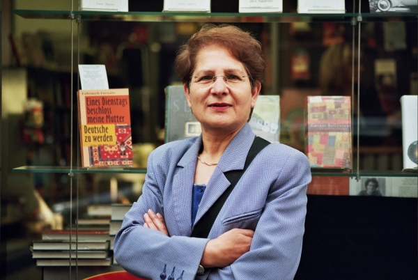 Eine Frau steht vor einer Buchhandlung mit Bücherregalen im Hintergrund.