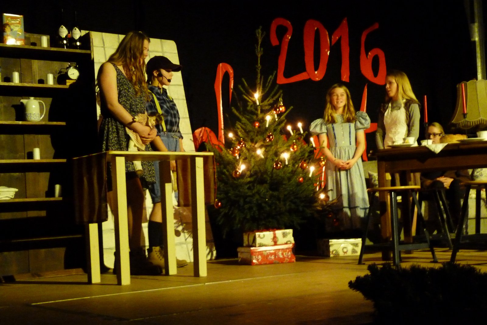 Schüler führen ein Theaterstück vor einem Weihnachtsbaum auf.
