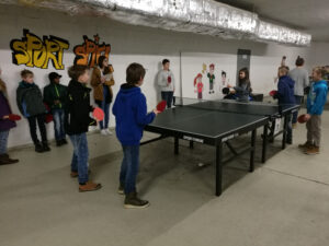 Tischtennis-Spieler in einer Sporthalle mit Graffiti-Wänden.