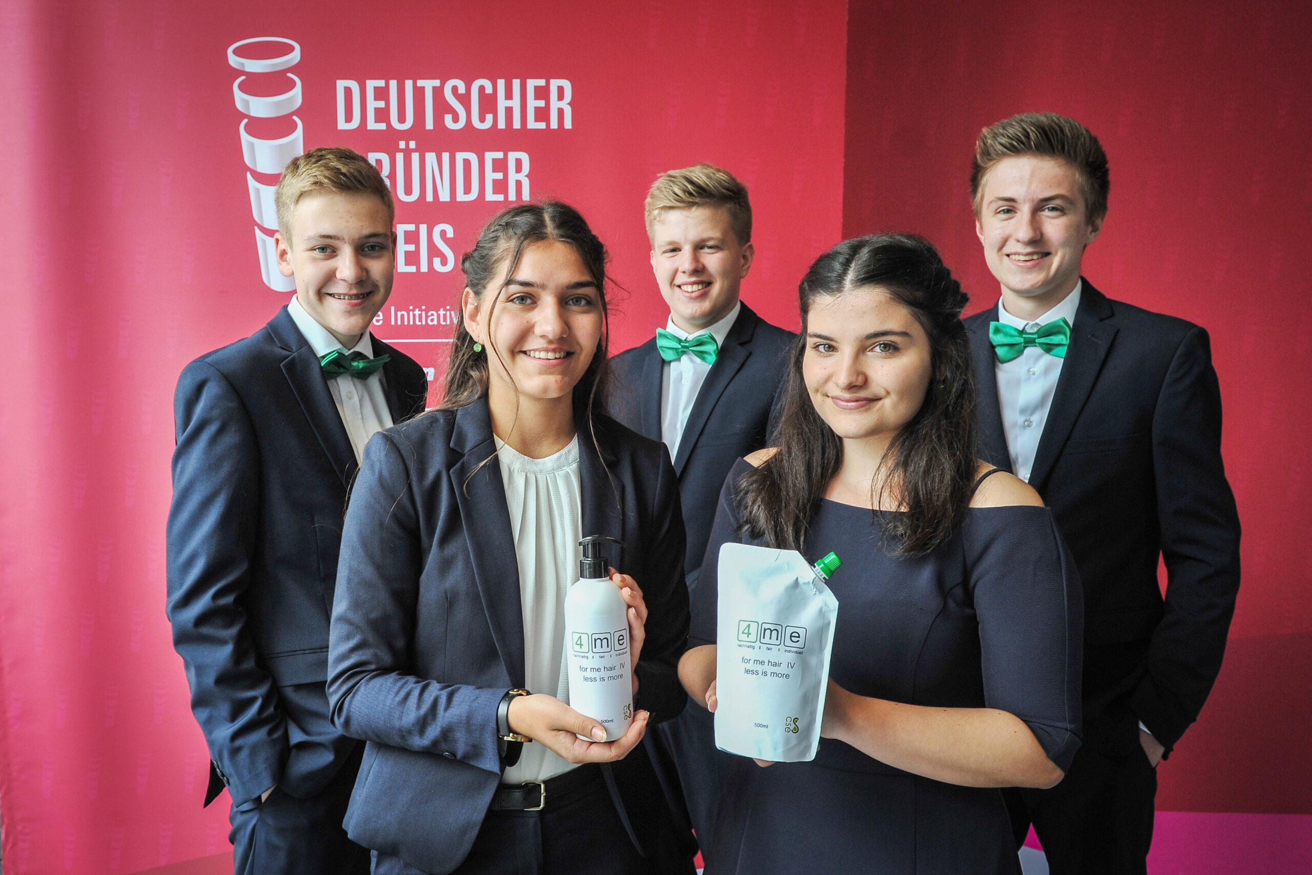 Fünf junge Leute in eleganter Kleidung halten Lebensmittelverpackungen vor einem roten Hintergrund.