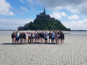 Gruppe von Schülern am Strand mit Mont Saint-Michel im Hintergrund.