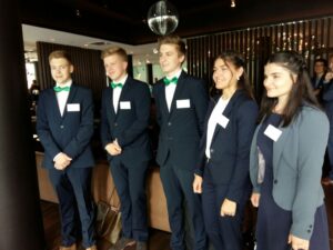 Gruppe junger Menschen in formeller Kleidung steht lächelnd zusammen.