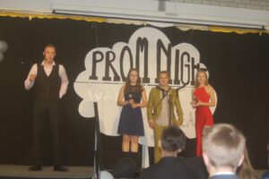 Schüler präsentieren Preise auf einer Bühne bei einer Abschlussveranstaltung.