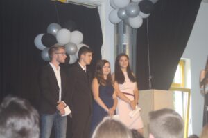 Vier Jugendliche stehen auf einer Bühne vor schwarzen und weißen Ballons.
