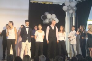 Schüler stehen auf der Bühne bei einer Veranstaltung, dekoriert mit Luftballons.