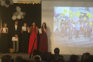 Schüler präsentieren auf der Bühne mit Ballons im Hintergrund.
