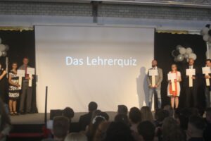 Szenenbild von einer Veranstaltung mit Lehrern und Publikum, Präsentation des Lehrerquiz.