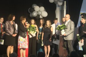 Feierliche Veranstaltung mit Rednerin und Absolventen auf der Bühne.
