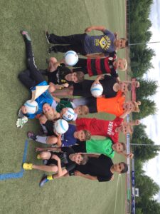 Gruppe von Kindern auf einem Fußballfeld, posierend mit Bällen.