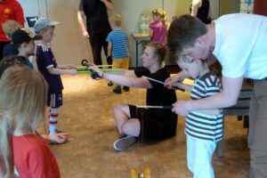 Kinder experimentieren mit Bändern und spielen miteinander in einem Raum.