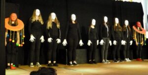 Schüler führen auf der Bühne eine Maskenperformance auf.