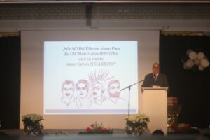 Mann spricht vor Präsentation mit Zeichnungen von historischen Personen.