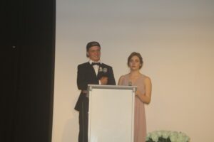 Zwei Personen stehen am Mikrofon auf einer Bühne.