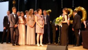 Abschlussfeier mit Schülern auf der Bühne und Goldballons.