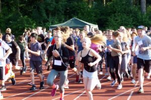 Schüler laufen auf einer Laufbahn, viele sind in Sportkleidung.