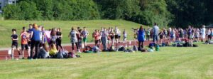 Schüler*innen auf einem Sportplatz beim Training oder Wettkampf.