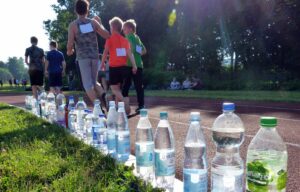 Läufer auf einer Laufbahn neben aufgereihten Wasserflaschen.