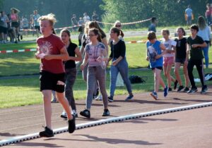 SchülerInnen laufen auf einer Sportbahn bei einem Lauf-Event.