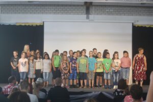 Gruppe von Kindern steht auf einer Bühne während einer Veranstaltung.