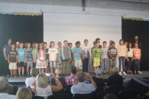 Schüler stehen auf der Bühne und präsentieren sich vor Publikum.