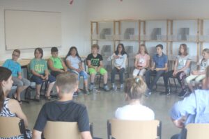 Gruppe von Schülern sitzt in einem Stuhlkreis in einem Klassenraum.