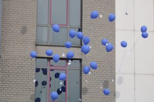 Luftballons in Blau schweben vor einem Gebäude mit Fenstern.