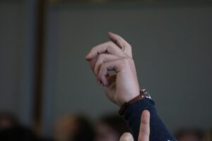 Ein erhobener Hand mit einem Armband im Vordergrund.