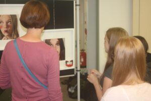 Personen betrachten Bilder in einer Ausstellung.
