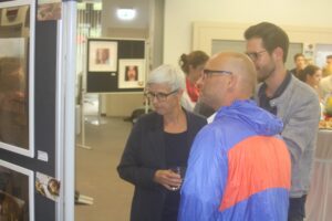 Personen betrachten Fotos bei einer Ausstellung.