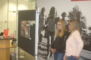 Zwei Frauen betrachten eine Ausstellungstafel in einem modernen Raum.