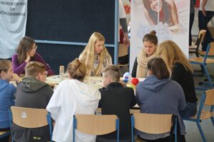 Schülerinnen und Schüler sitzen an einem Tisch und arbeiten an einem Projekt.